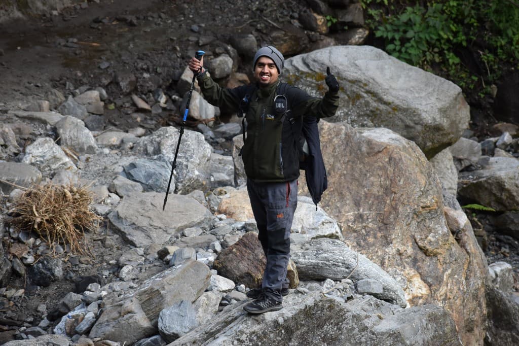 Pratap Sharma standing on boulders with a thumbs up on the ABC trail