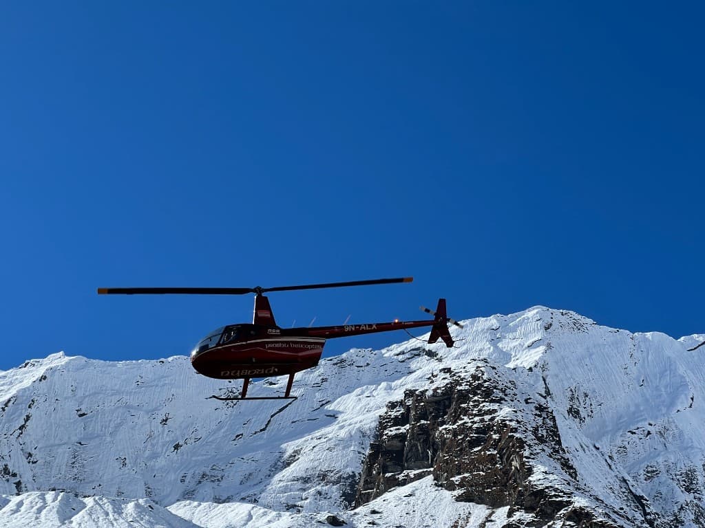 Red Prabhu helicopter flying past snow-covered Annapurna peaks