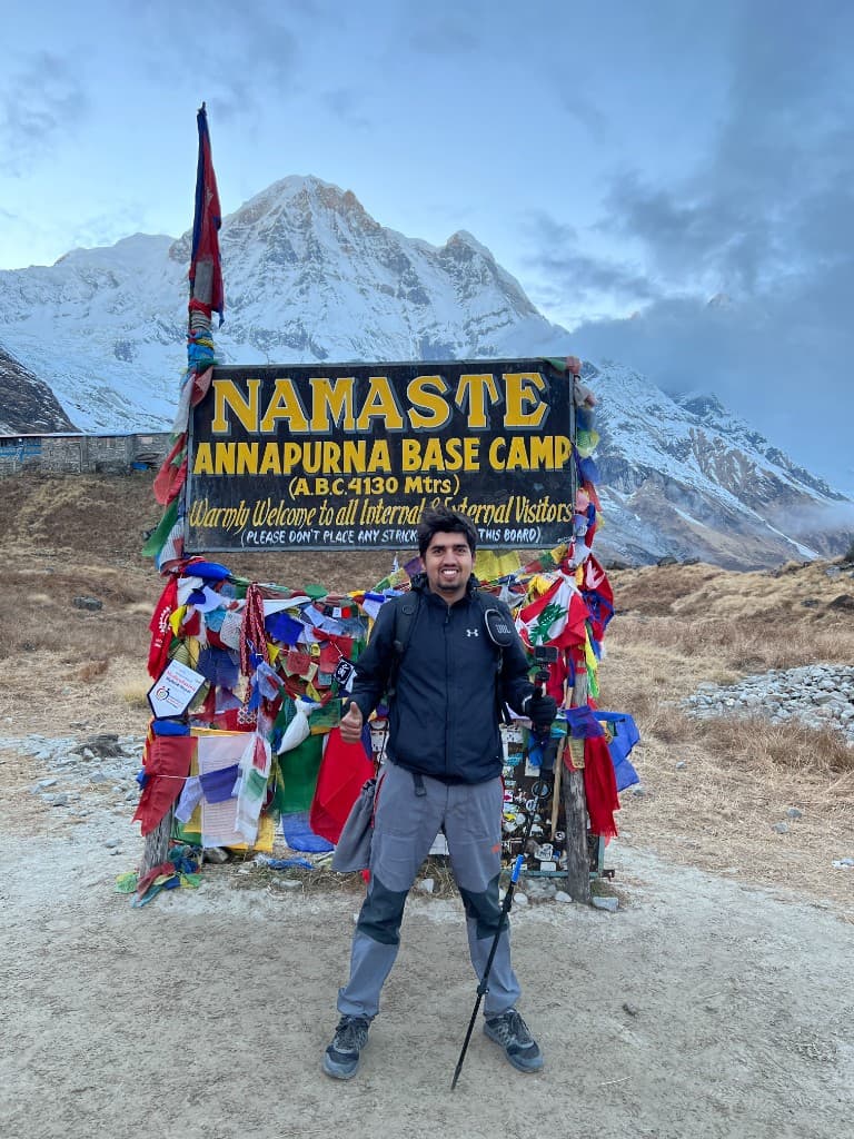Pratap Sharma giving a thumbs up at the Annapurna Base Camp sign after arriving