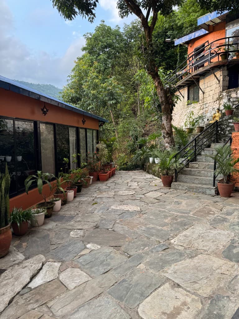 Serene stone courtyard pathway surrounded by lush greenery at Yogaban Retreat Pokhara