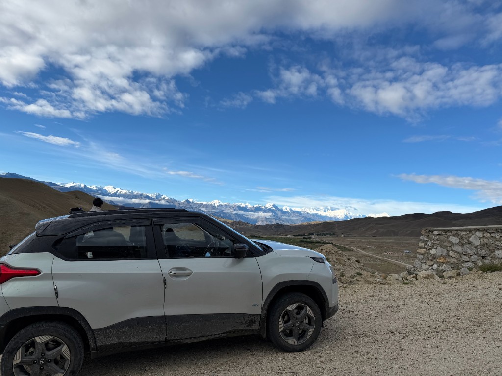 Dusty Punch EV parked with snow-capped Himalayan peaks behind