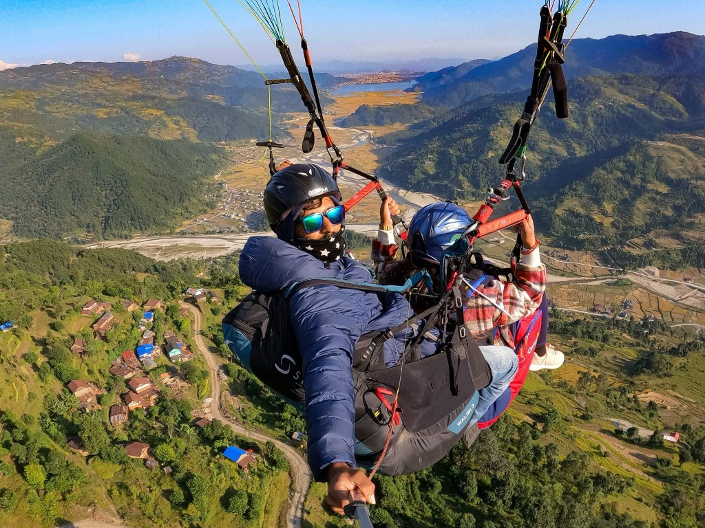 Tandem paragliding over terraced hills and villages in the Pokhara valley