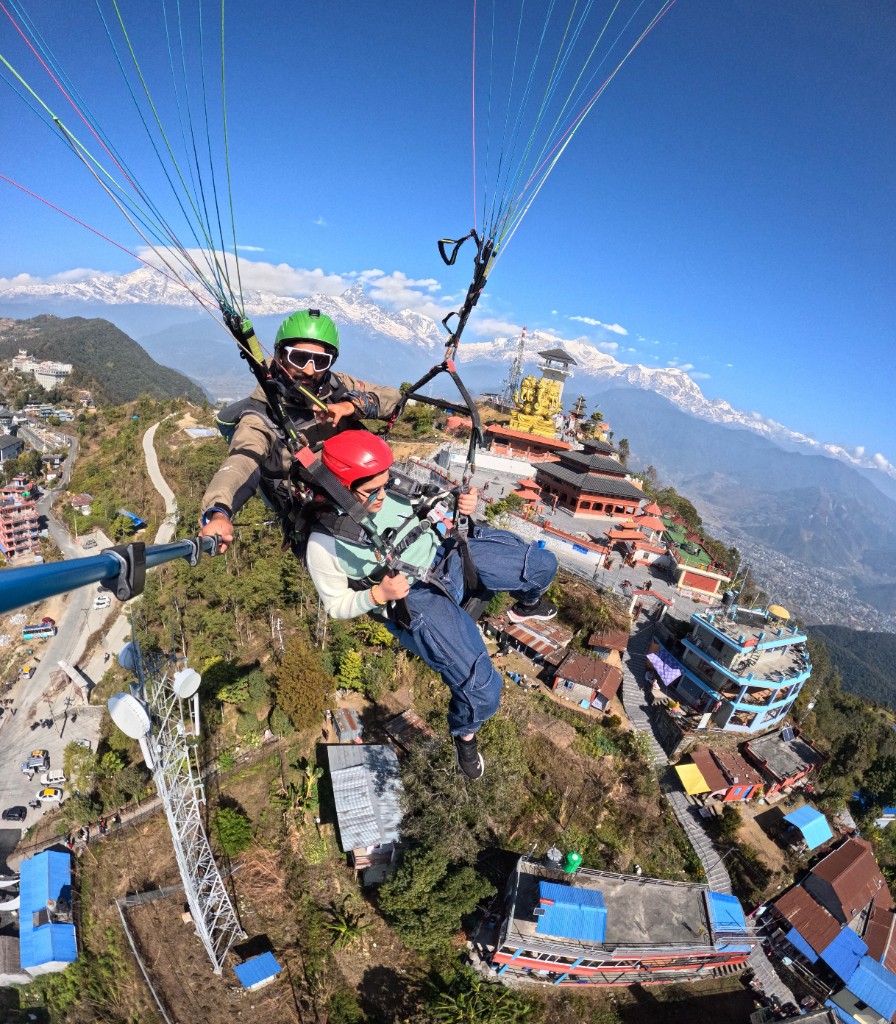 Tandem paragliding above the Pumdikot Shiva statue with Annapurna range in the background