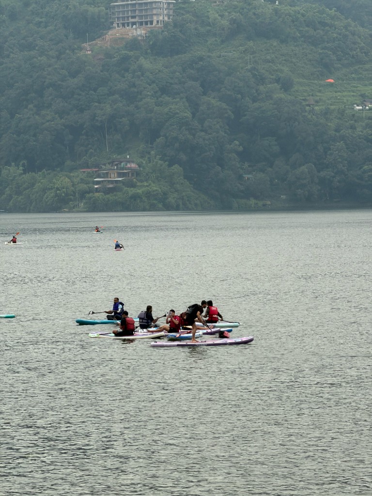Friends on colourful stand-up paddleboards clustered together on calm lake water